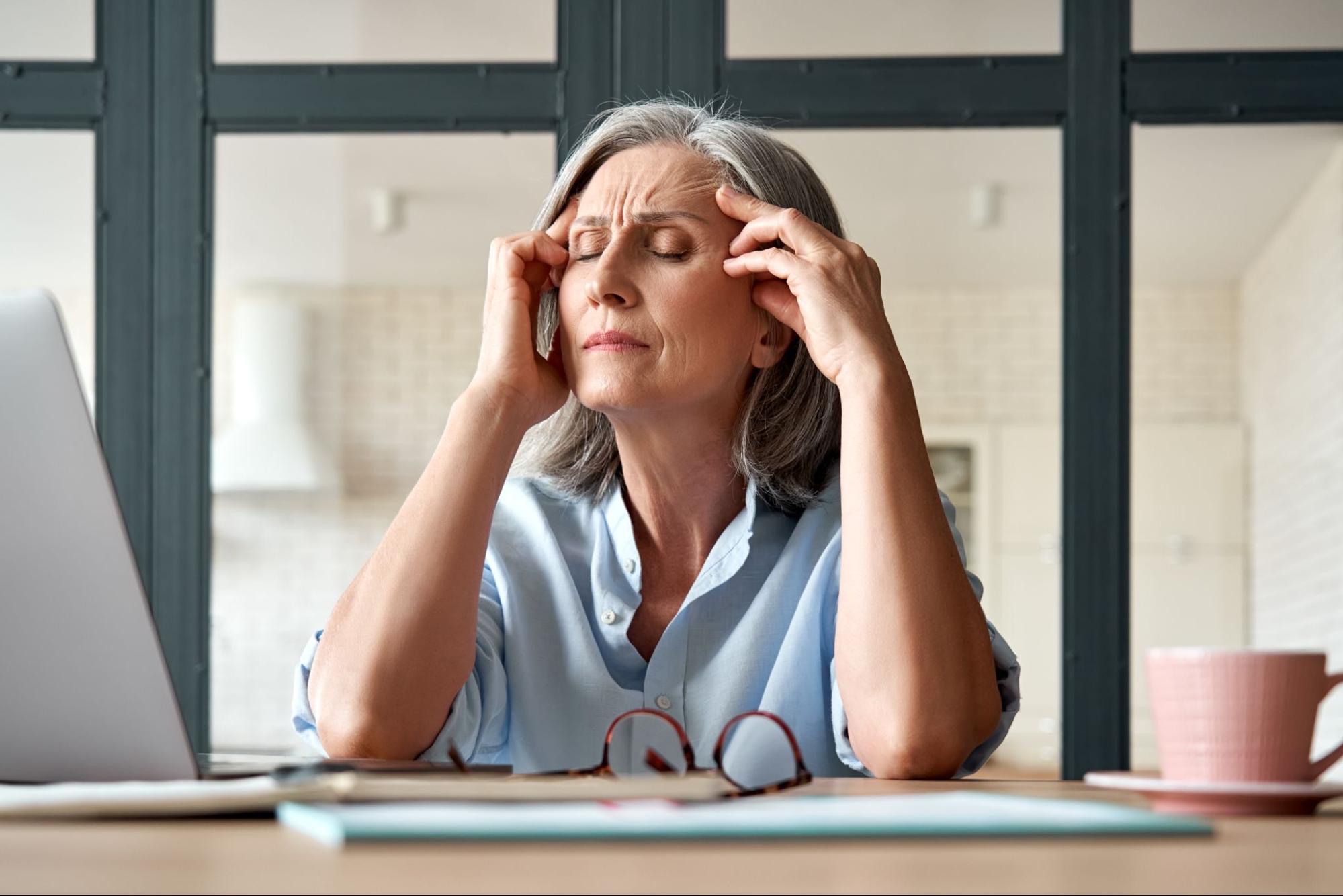 An older adult closes their eyes and experiences mild cognitive impairment while on the phone.